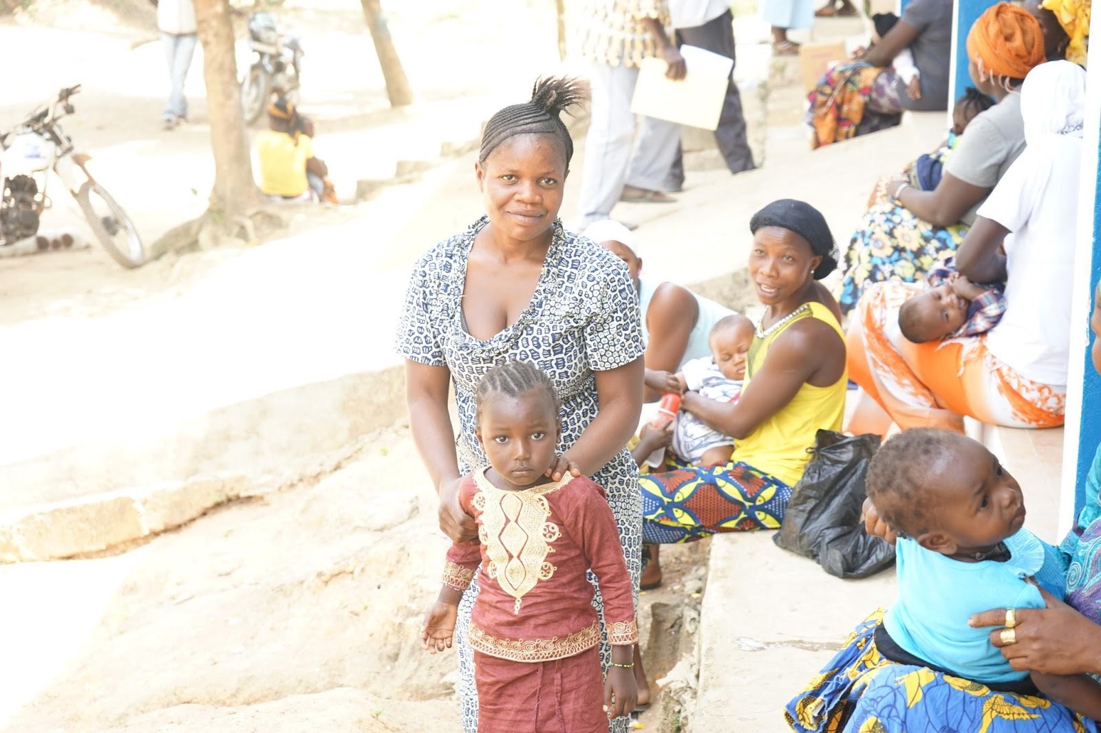 A mother and child gather with others outside of the Wellbody Clinic.