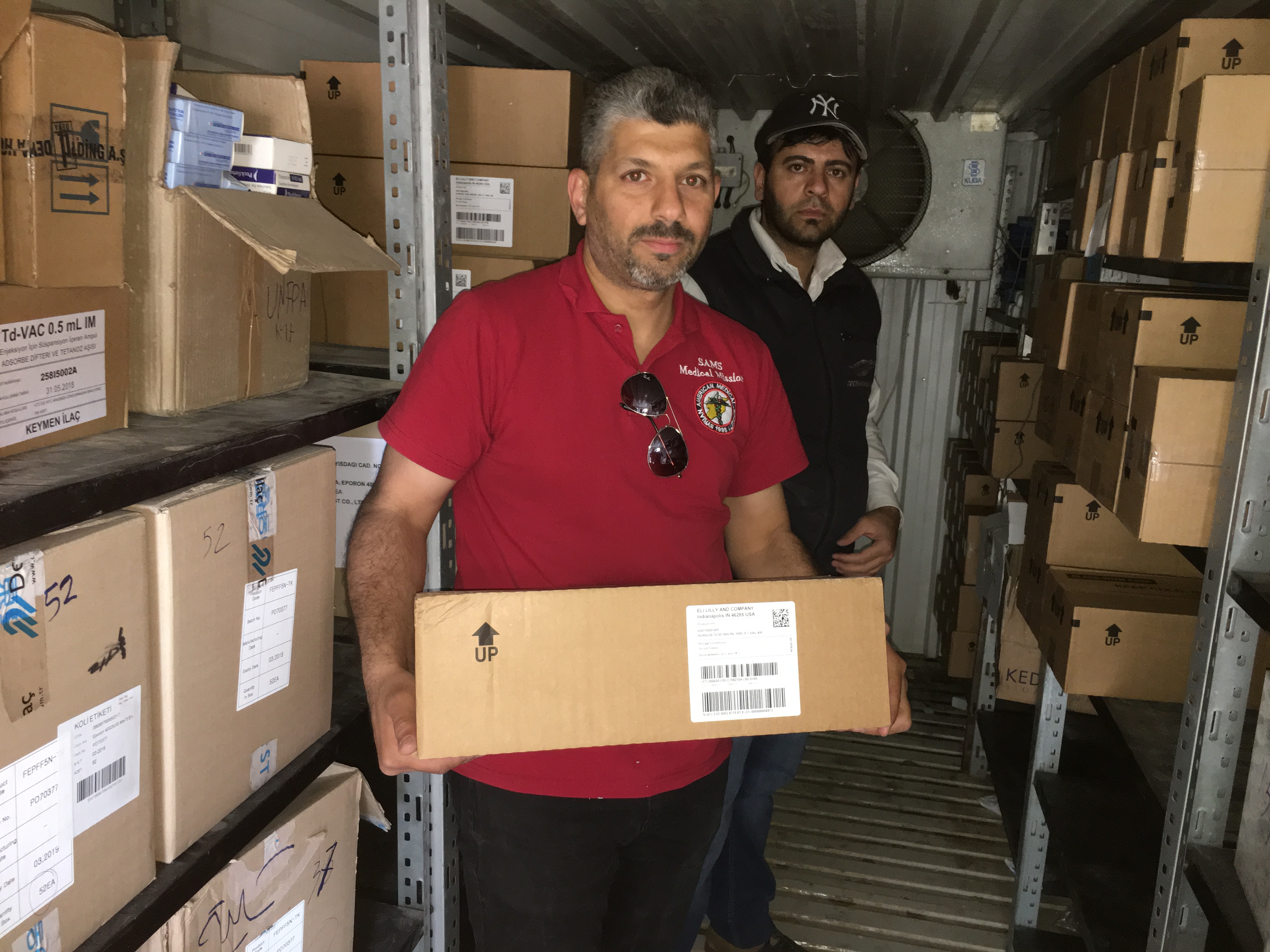 A staff pharmacist from the Syrian American Medical Society holds a case of insulin donated by Direct Relief and Life for a Child inside SAMS’ cold storage facility inside Syria on April 25, 2018. (Photo courtesy of the Syrian American Medical Society)
