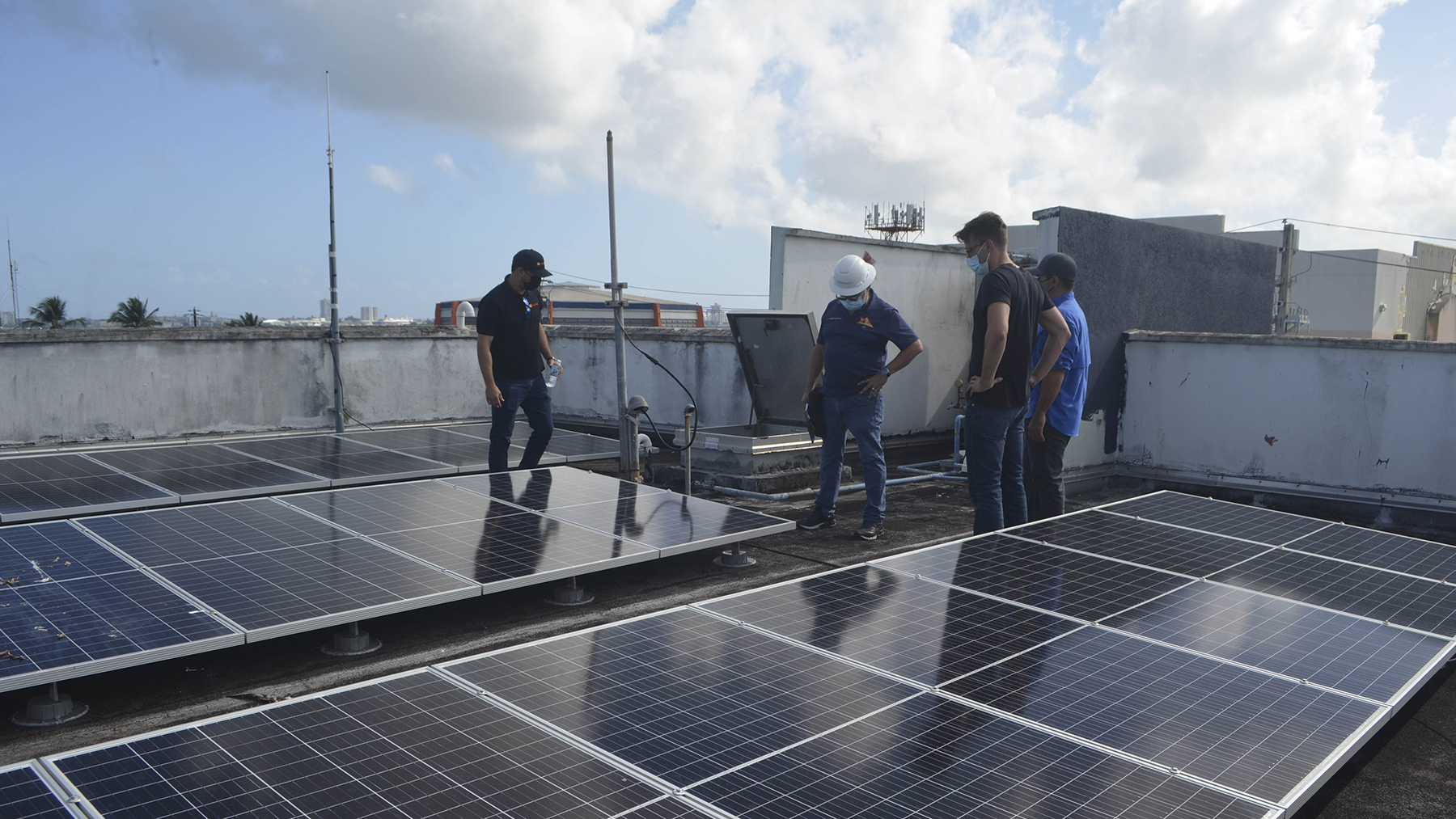 Firefighters at the Cataño fire station in Puerto Rico and a Direct Relief staff member examine solar panels newly installed on the station roof. (Ana Umpierre/Direct Relief)