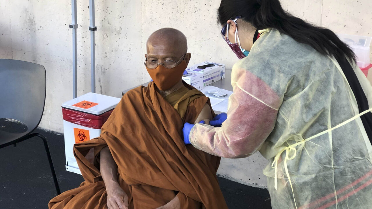 A Thai monk receives a vaccination from Kheir Center staff as part of the health center's outreach to specific patient populations. (Photo courtesy of Kheir Center)
