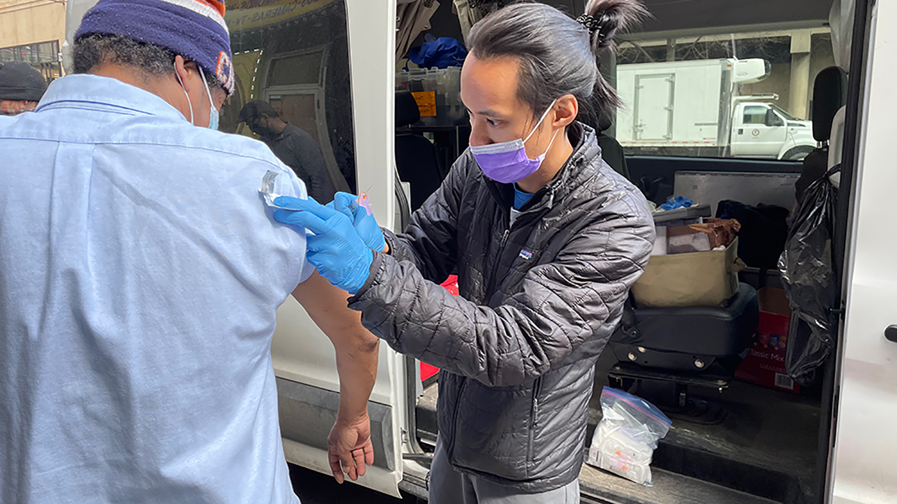 Dr. Nathan Lin (right), a medical resident, prepares a Covid-19 vaccine for a street medicine patient. Lin works with the Night Ministry, which provides health care and supportive services to Chicago’s unsheltered homeless population. The organization received financial support from the Fund for Health Equity to expand its efforts. (Courtesy photo)