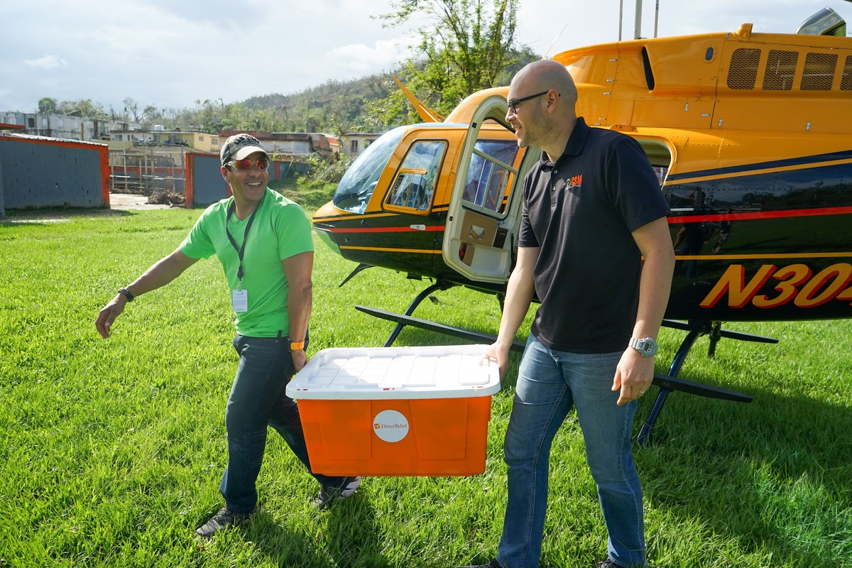 Daniel Ramos of the Puerto Rico Primary Care Association and Alexis Romero of the Corporacion de Servicios Medicos, a clinic in Utuado, unload medicines from a helicopter, provided by Samaritan’s Purse. (Lara Cooper/Direct Relief)
